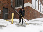 David Smith shovels the sidewalk as the first snow falls ahead of a winter storm on Tuesday, Feb. 21, 2023, in Sioux Falls, S.D.  A wide swath of the Upper Midwest is bracing for a historic winter storm. The system is expected to bury parts of the region in 2 feet of snow, create dangerous blizzard conditions and bring along bitter cold temperatures.