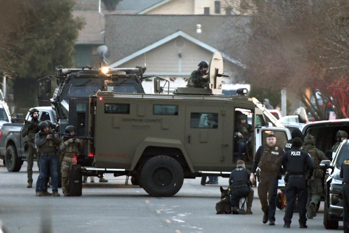 Law enforcement officers aim their weapons at a home during a standoff in Grants Pass, Ore., on Tuesday, Jan. 31, 2023.