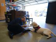 Adam Holwuttle, 35, spends time with Apollo on Jan. 27 in the garage at a Merakey company home in Escondido, Calif. Holwuttle and his housemates have been training Apollo so that he can be placed for adoption. (Nelvin C.