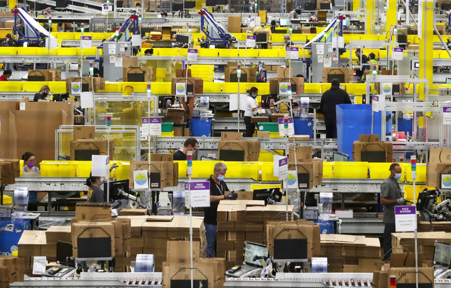 Employees work at packing stations at Amazon's Kent fulfillment center, BFI4, in June 2020. Workers there are asked to repeatedly lift, carry and twist at a pace that drives up injury rates, Labor and Industries officials said in a citation for that facility.