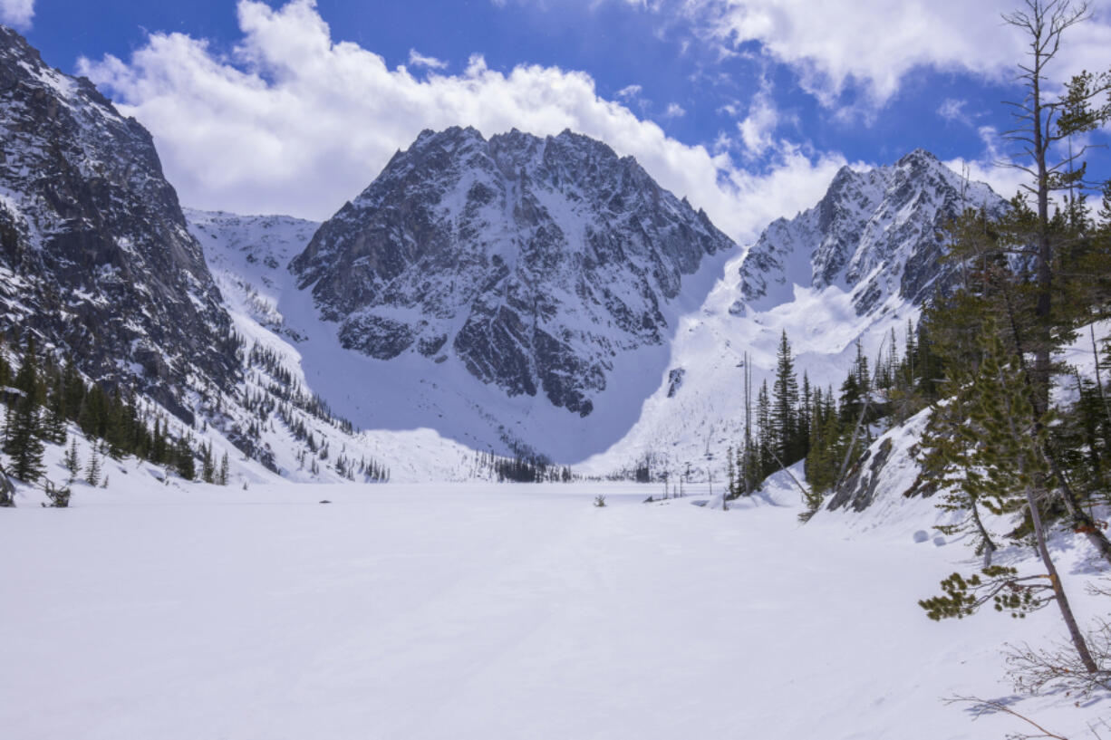 Dragontail Peak rises above frozen Colchuck Lake under bright sunshine in northern Cascade Mountains near Wenatchee, Washington, in April 2017.