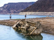 Hikers pass a previously sunken World War II-era Higgins landing craft that once was 185 feet below the surface is nearly on the shoreline as waters keep receding on July 26, 2022, near Boulder City, Nevada. (L.E.