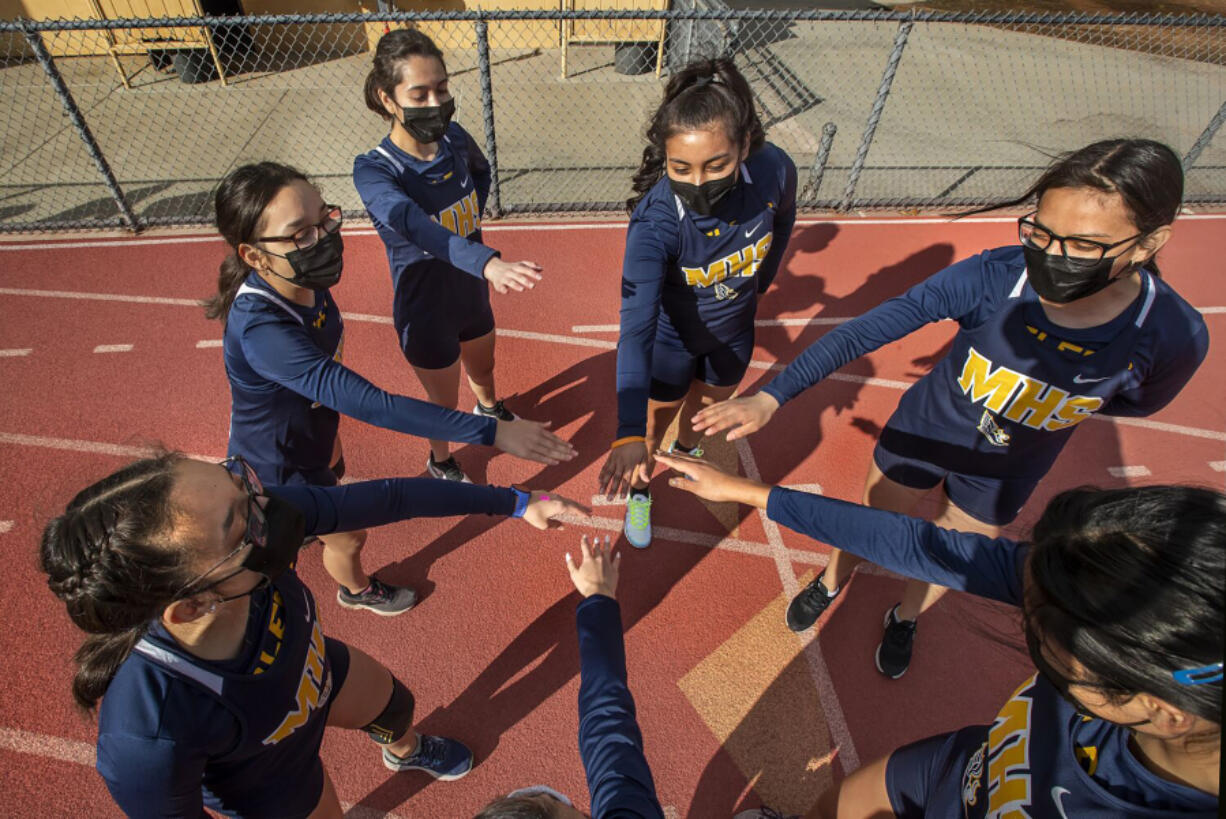 Members of the Montebello High School girls cross country team are careful not to touch hands while wearing masks as they huddle up before a home meet against Bell Gardens High School. Montebello Unified starting to bring students back for athletic events.