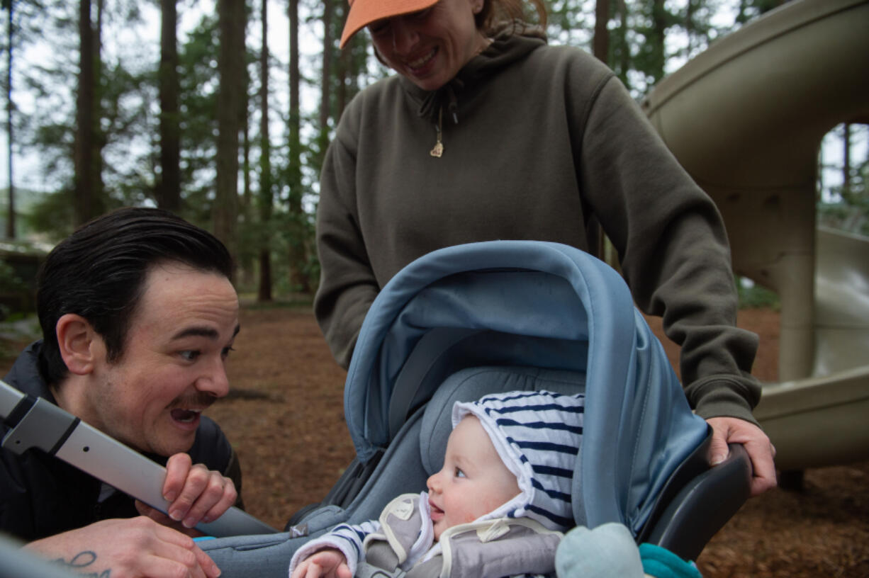 Dylan Alexander and Jona Tochet smile at their youngest, Bowie, while enjoying family time at the park. Alexander recently published a book about how to incorporate a healthier lifestyle into daily family life.