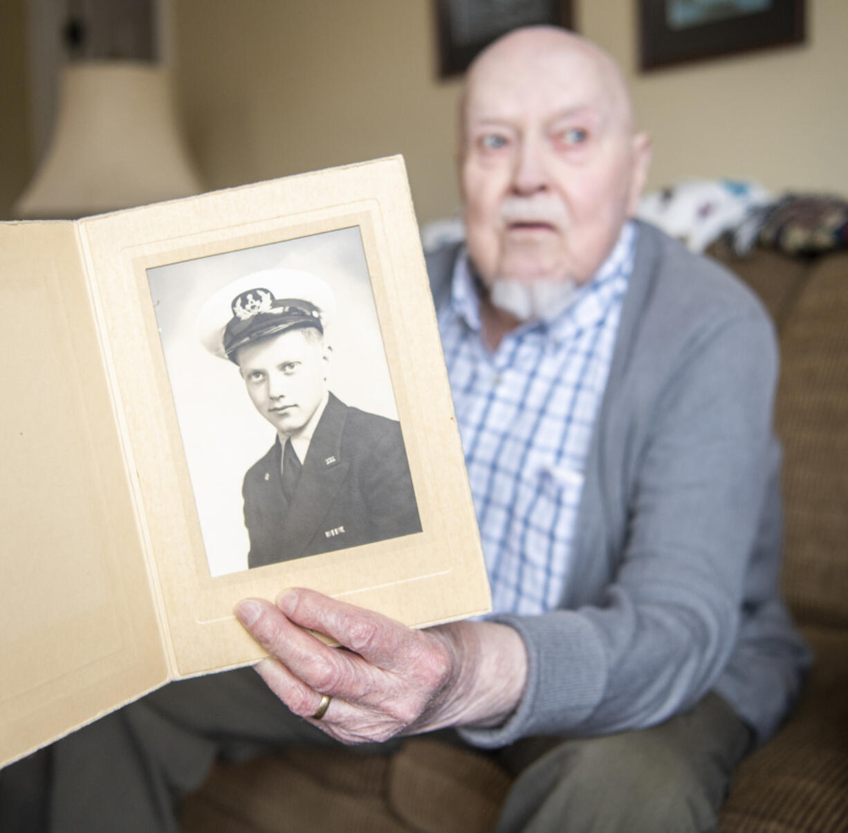 Julian Thorne Hilts holds up a photo of himself in his apartment. Thorne received a Congressional Gold Medal last year for his service in the merchant marines in World War II.