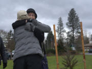 Barbara Rhoden, left, and Adrienne Strehlow share an embrace at a Vancouver Heights tree dedication in honor of Rhoden's deceased husband, Vaughn, and all those in the county who have lost their lives to the coronavirus.