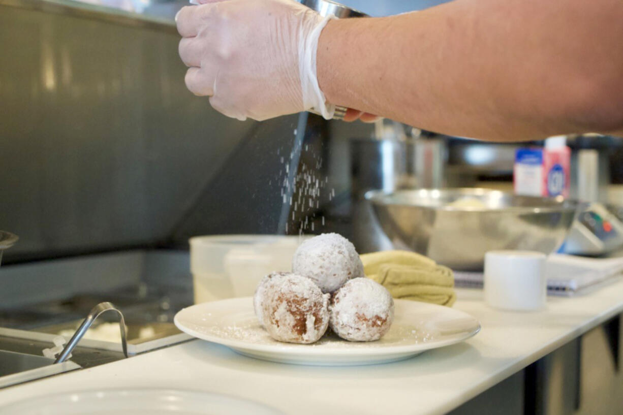 Donuts receive a sprinkle of powdered sugar before leaving the kitchen at Cecilia.