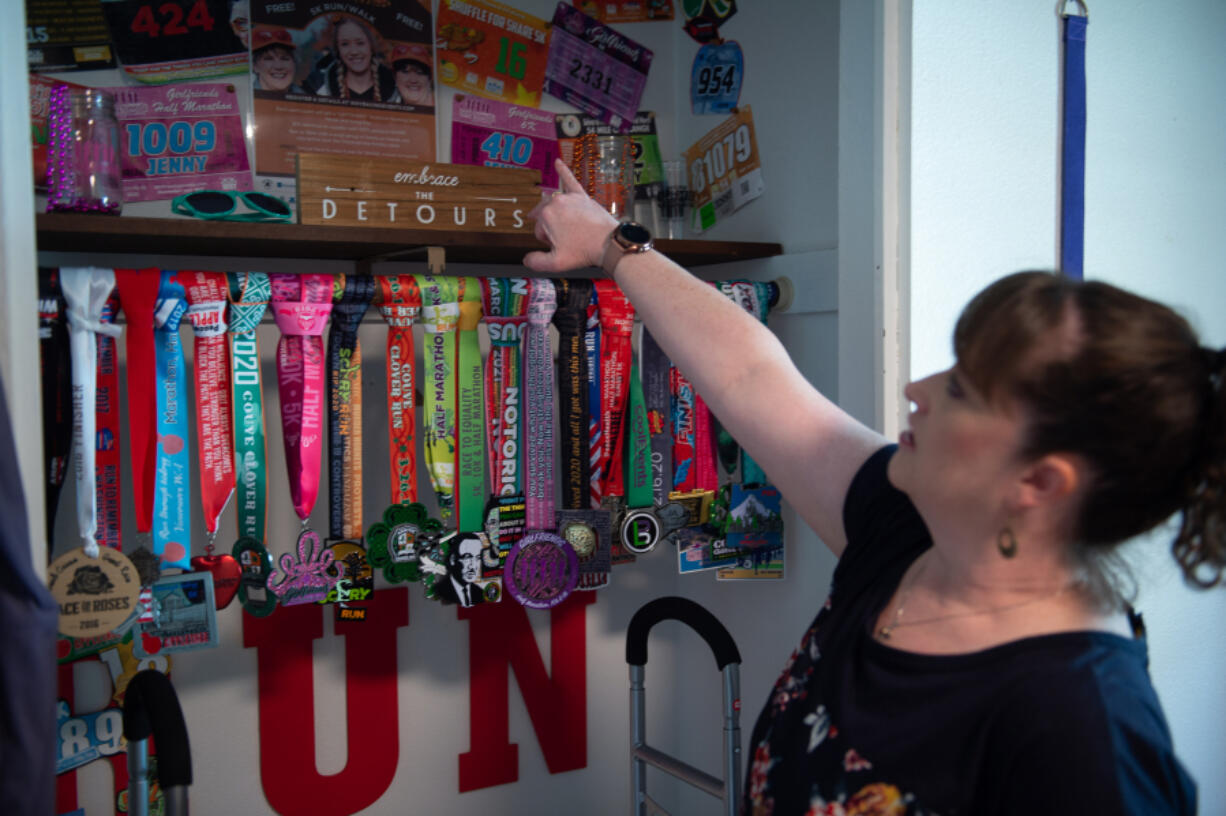 Jenny Bevard shows off her collection of marathon and half-marathon medals in her Vancouver home. Before getting long COVID, she was an avid runner. Now, even a walk inside from the car can leave her short of breath.