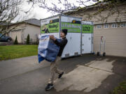 Xavier Lopez of Miracle Man Movers carries a piece of furniture for a customer moving from Washougal to Vancouver. The company moves people all over the region but has helped more clients make the journey from Oregon to Washington than the other direction.