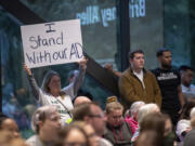 An audience members holds up a sign in support of athletic directors Tuesday during an Evergreen Public Schools meeting at Evergreen Public Schools headquarters.