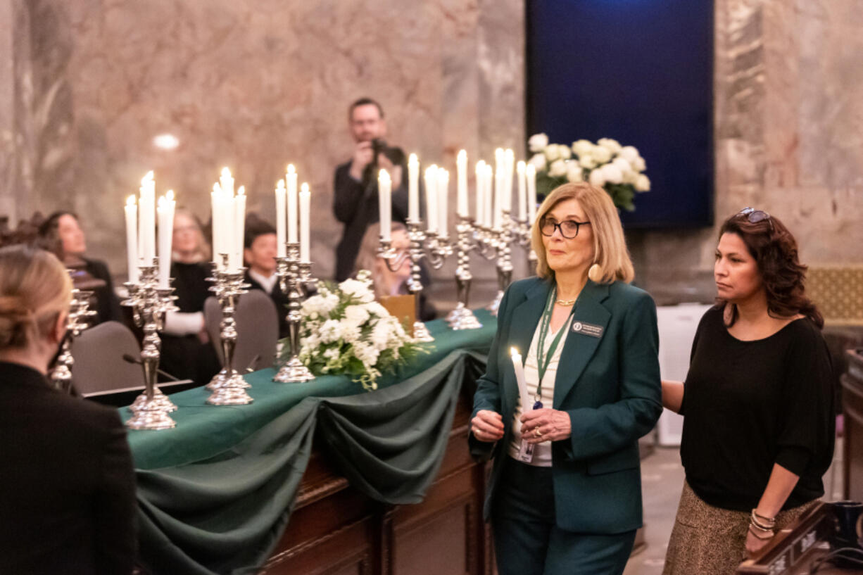 Reps. Sharon Wylie and Monica Stonier prepare to light a candle in memory of the late Rep. Jim Moeller during a joint memorial session at the Capitol on Wednesday.