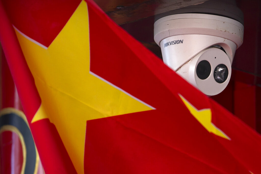 FILE - A Chinese flag hangs near a security camera outside of a shop in Beijing on Oct. 8, 2019. China has long been seen by the U.S. as a prolific source of anti-American propaganda but less aggressive in its influence operations than Russia, which has used cyberattacks and covert operations to disrupt U.S. elections and denigrate rivals. But many in Washington now think China is increasingly adopting tactics associated with Russia — and there's growing concern the U.S. isn't doing enough to respond.