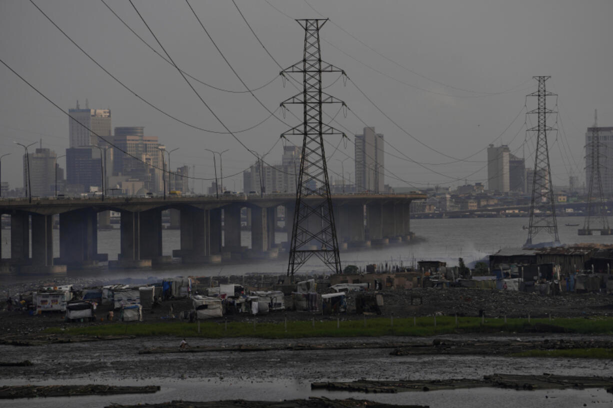 FILE - High tension power lines pass through Makoko slum in Lagos, Nigeria, Saturday, Aug. 20, 2022. From Zimbabwe, where many must work at night because i t's the only time there is power, to Nigeria where collapses of the grid are frequent, the reliable supply of electricity remains elusive across Africa.