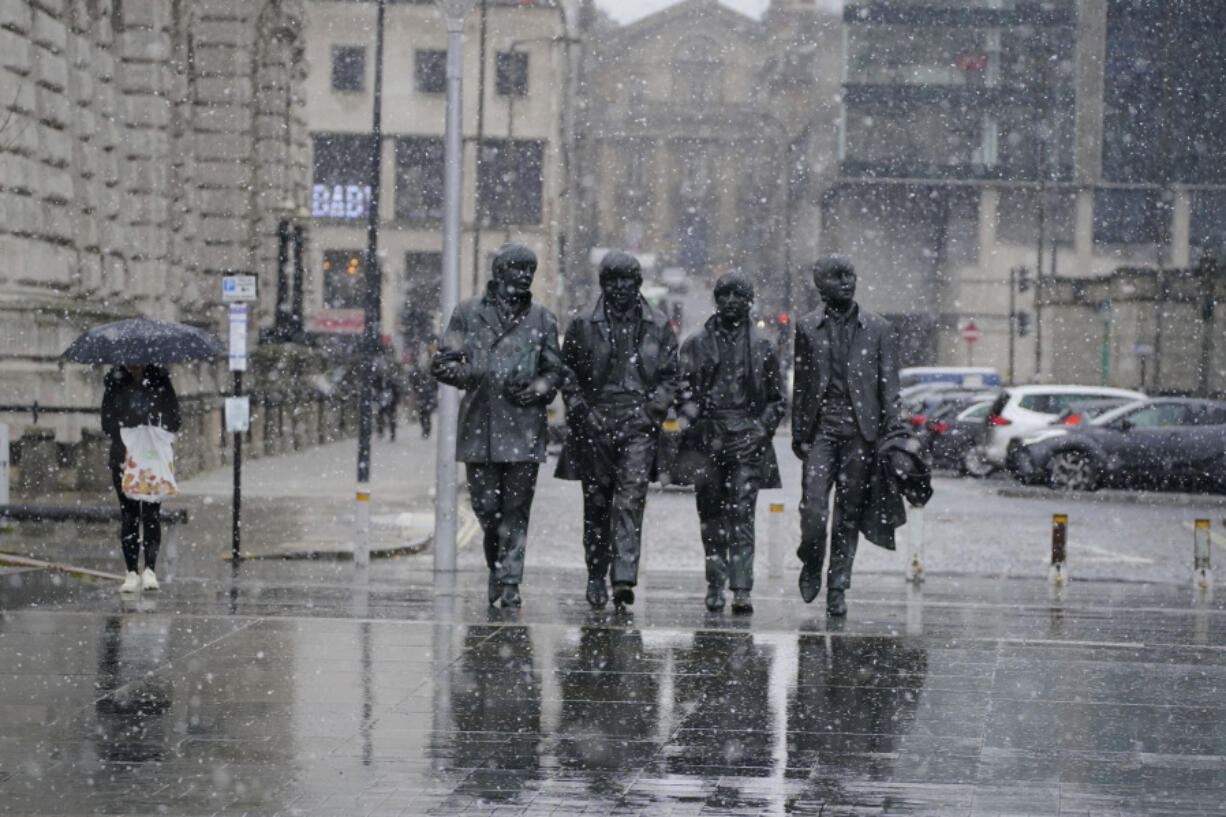 Snow falls around the statue of the British group The Beatles, at Pier Head in Liverpool, England, Thursday March 9, 2023. The UK is set to experience severe snowstorms and travel disruption as the Met Office has issued an amber warning in some areas.