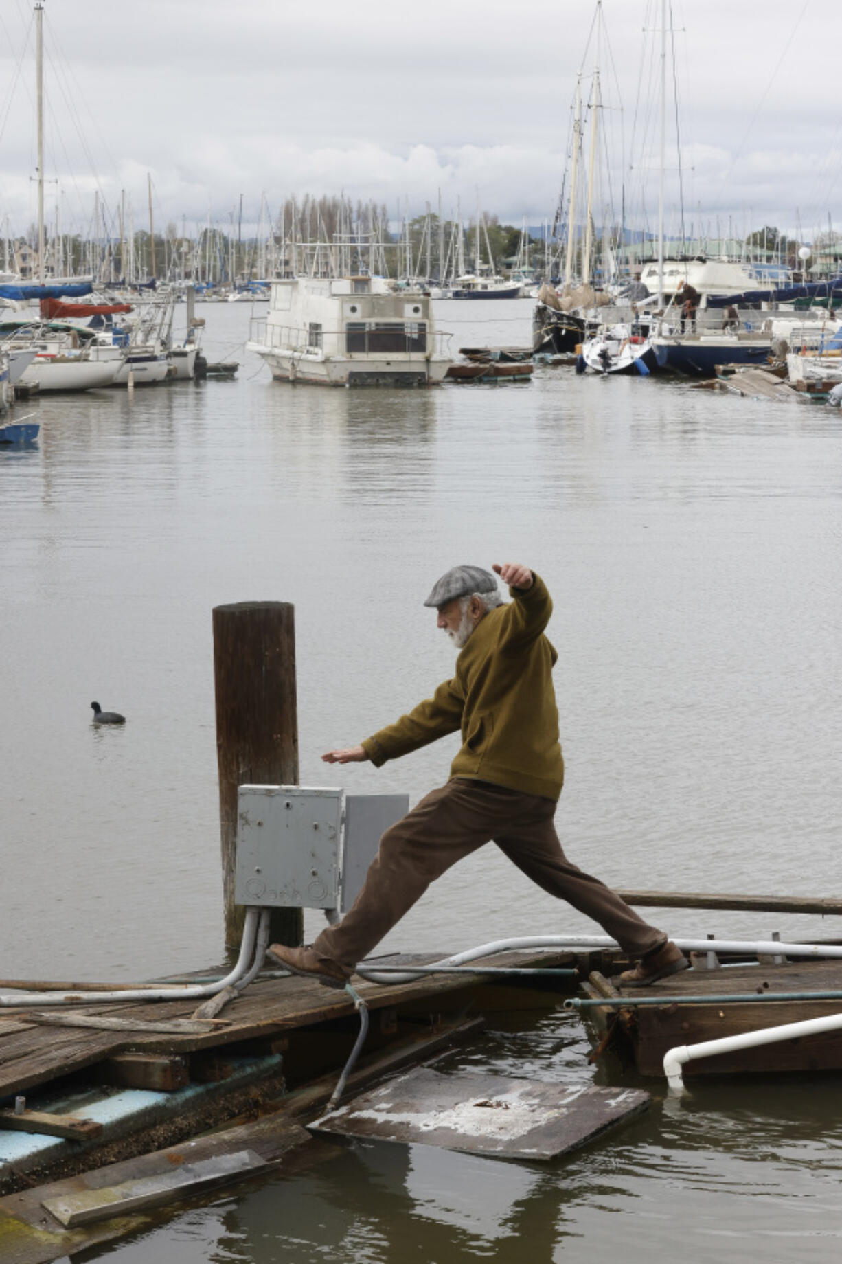 Stewart Port leaps over a broken dock at 5th Avenue Marina on Wednesday, March 22, 2023, in Oakland, Calif. Rare and violent weather came amid a strong late-season Pacific storm that brought damaging winds and more rain and snow to saturate California.