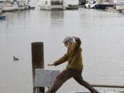 Stewart Port leaps over a broken dock at 5th Avenue Marina on Wednesday, March 22, 2023, in Oakland, Calif. Rare and violent weather came amid a strong late-season Pacific storm that brought damaging winds and more rain and snow to saturate California.