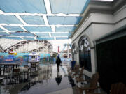 A worker walks among a vacant Belmont Park as rain engulfs the area, Tuesday, March 21, 2023, in San Diego. Californians are tired. Tired of the rain, tired of the snow, tired of stormy weather and the cold, relentlessly gray skies that have clouded the Golden State nearly nonstop since late December.