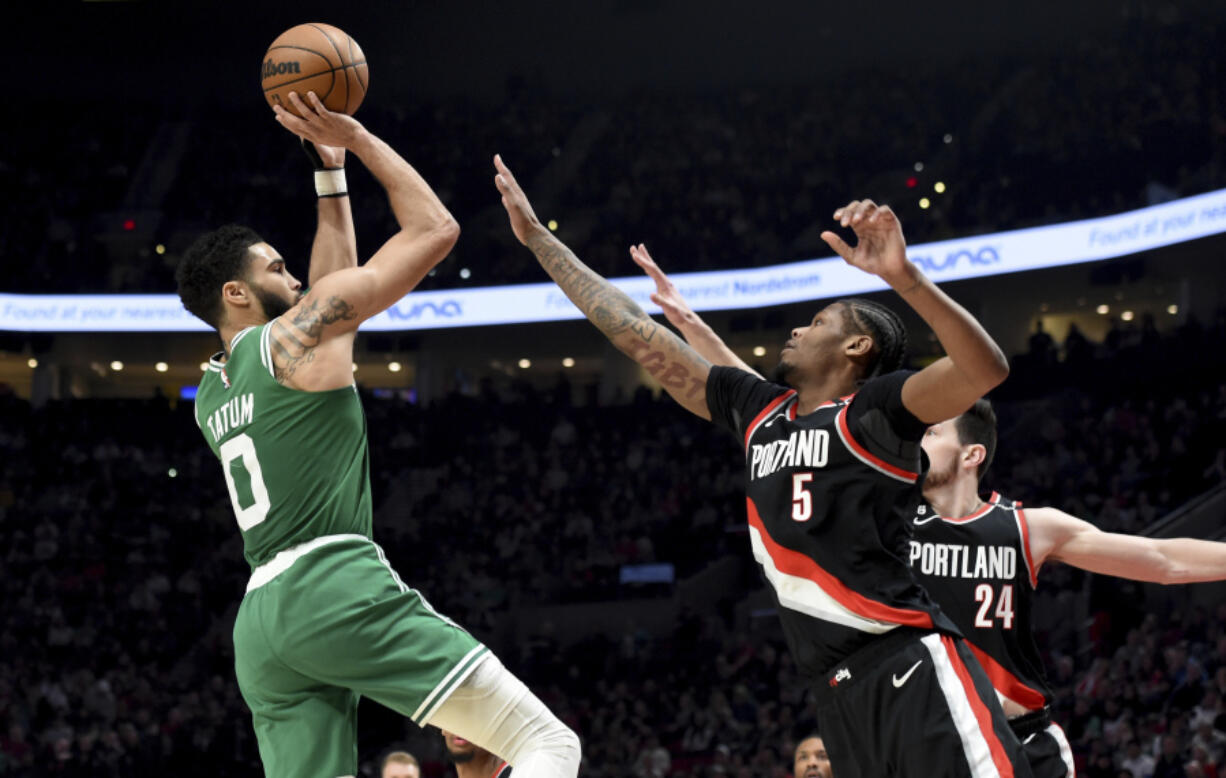 Boston Celtics forward Jayson Tatum, left, prepares to shoot a basket over Portland Trail Blazers forwards Cam Reddish, center, and Drew Eubanks, right, during the first half of an NBA basketball game in Portland, Ore., Friday, March 17, 2023.