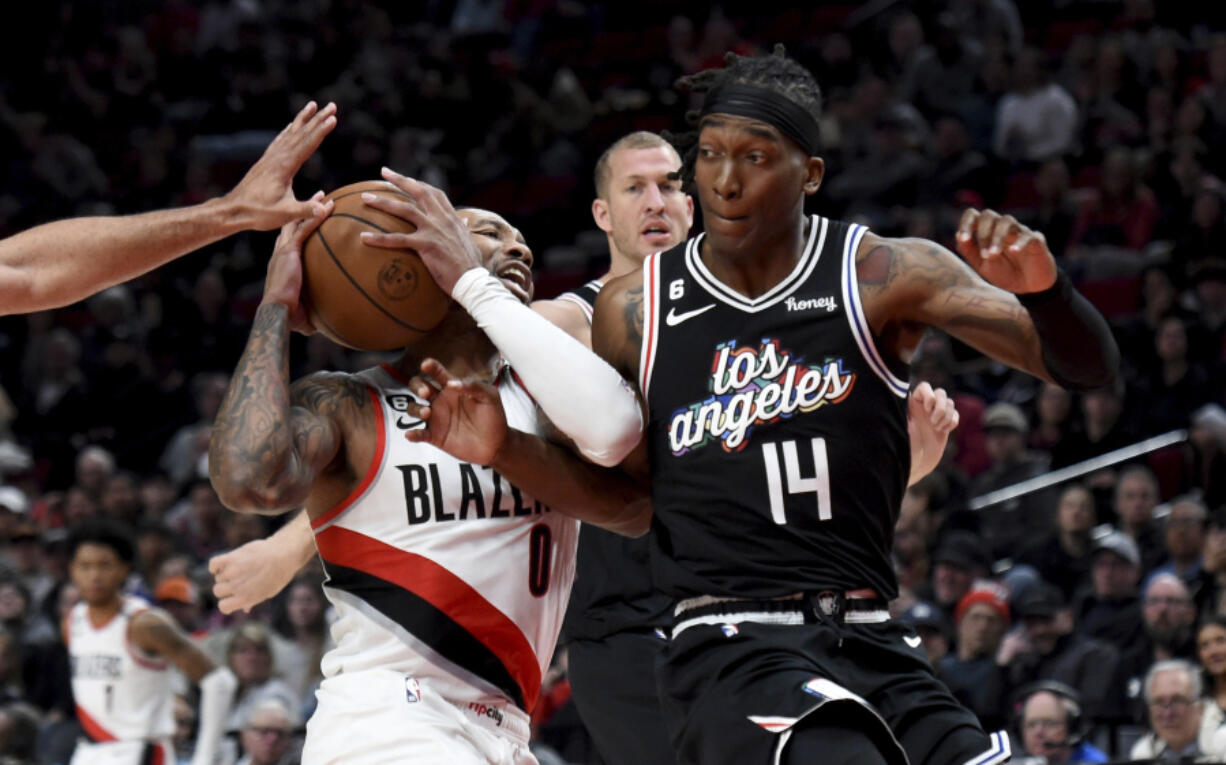 Portland Trail Blazers guard Damian Lillard, left, drives against Los Angeles Clippers guard Terance Mann, right, during the first half of an NBA basketball game in Portland, Ore., Sunday, March 19, 2023.