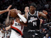 Portland Trail Blazers guard Damian Lillard, left, drives against Los Angeles Clippers guard Terance Mann, right, during the first half of an NBA basketball game in Portland, Ore., Sunday, March 19, 2023.