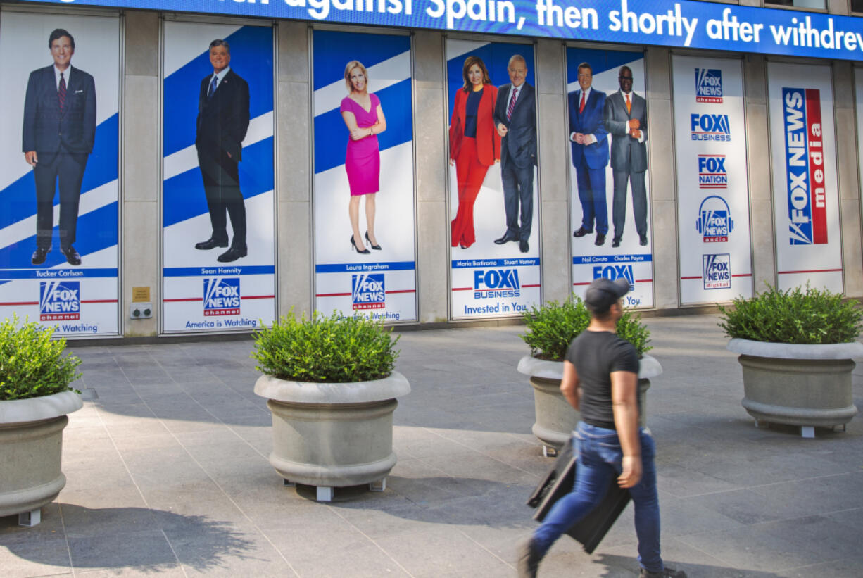 FILE - Images of Fox News personalities, from left, Tucker Carlson, Sean Hannity, Laura Ingraham, Maria Bartiromo, Stuart Varney, Neil Cavuto and Charles Payne appear outside News Corporation headquarters in New York on July 31, 2021. In defending itself against a massive defamation lawsuit over how Fox covered false claims surrounding the 2020 presidential election, the network is relying on a 1964 Supreme Court ruling that makes it difficult to successfully sue media organizations for libel.