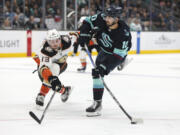 Seattle Kraken center Matty Beniers (10) shoots as Anaheim Ducks defenseman Simon Benoit (13) defends during the fist period of an NHL hockey game Thursday, March 30, 2023, in Seattle.