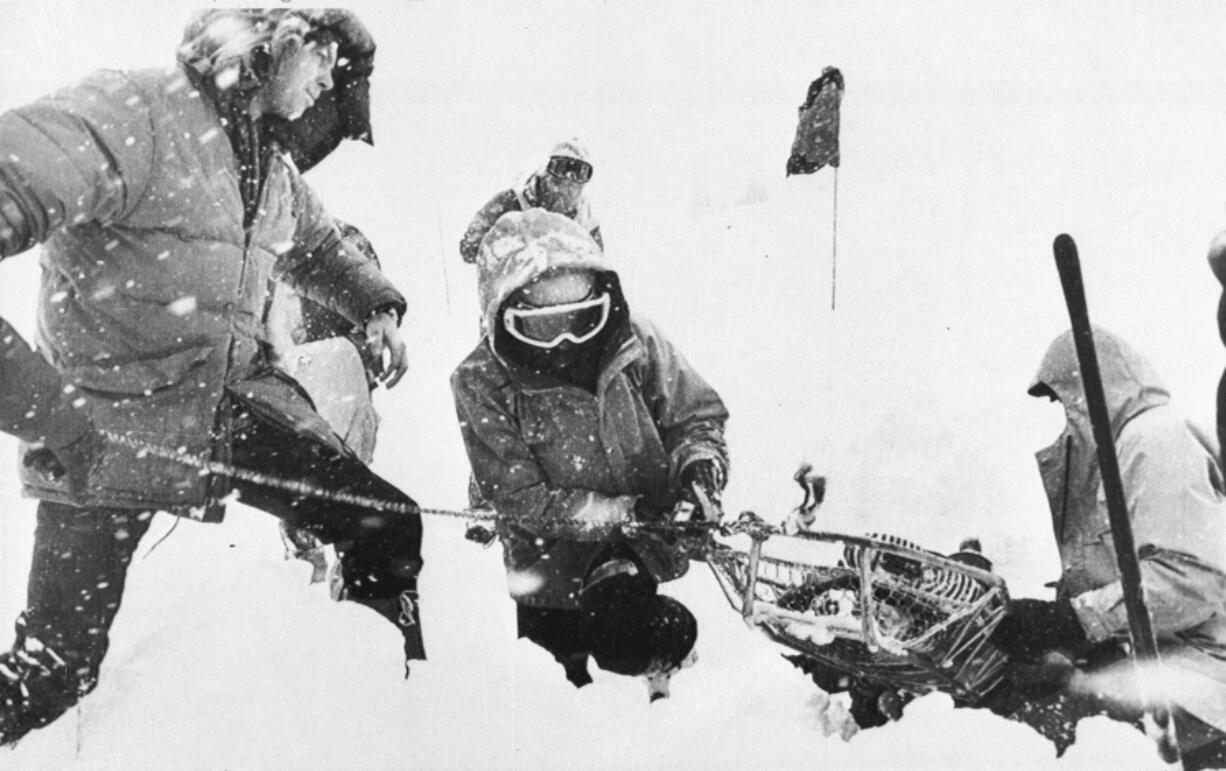 FILE - Rescue workers recover a body April 2, 1982, buried in the parking lot of the Alpine Meadows ski resort after an avalanche that killed seven people rolled through the area in the Sierra Nevada mountains near Palisades Tahoe, Calif. The Alpine avalanche on March 31, 1982, was the deadliest avalanche to sweep through a ski area. Since December 2022, a parade of a dozen atmospheric storms have dumped so much snow up and down the Sierra that several ski resorts around Lake Tahoe have had to shut down multiple times.