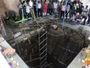 People stand around a structure built over an old temple well that collapsed Thursday as a large crowd of devotees gathered for the Ram Navami Hindu festival in Indore, India, Thursday, March 30, 2023. Up to 35 people fell into the well in the temple complex when the structure collapsed and were covered by falling debris, police Commissioner Makrand Deoskar said. At least eight were killed.