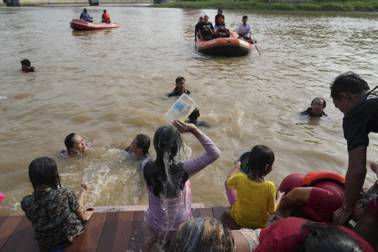 People bathe in the Cisadane River, ahead the holy fasting month of Ramadan in Tangerang, Indonesia, Tuesday, March 21, 2023. Muslims followed local tradition to wash in the river to symbolically cleanse their soul prior to entering the holiest month in Islamic calendar.