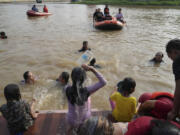 People bathe in the Cisadane River, ahead the holy fasting month of Ramadan in Tangerang, Indonesia, Tuesday, March 21, 2023. Muslims followed local tradition to wash in the river to symbolically cleanse their soul prior to entering the holiest month in Islamic calendar.