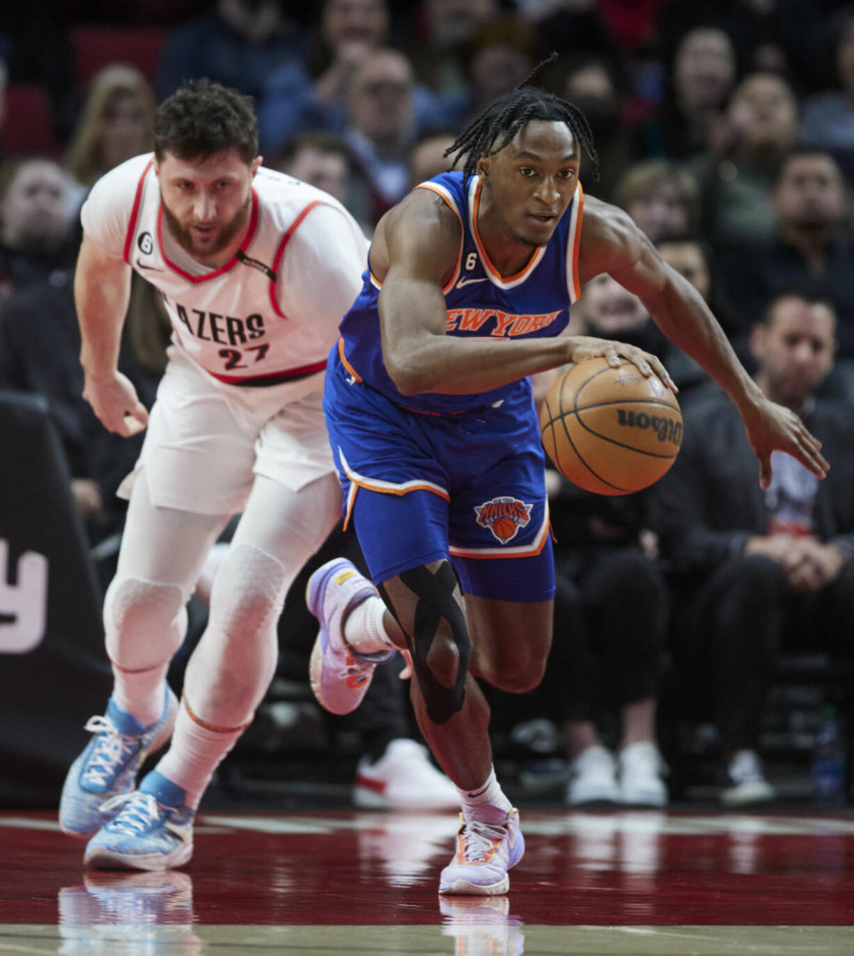 New York Knicks guard Immanuel Quickley, right, dribbles in front of Portland Trail Blazers center Jusuf Nurkic during the first half of an NBA basketball game in Portland, Ore., Tuesday, March 14, 2023.