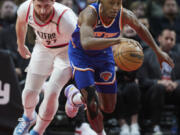 New York Knicks guard Immanuel Quickley, right, dribbles in front of Portland Trail Blazers center Jusuf Nurkic during the first half of an NBA basketball game in Portland, Ore., Tuesday, March 14, 2023.