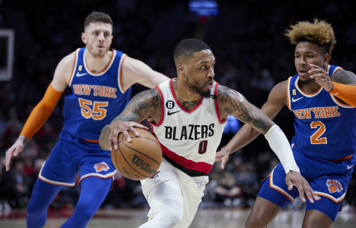 Portland Trail Blazers guard Damian Lillard, center, drives to the basket between New York Knicks guard Miles McBride, right, and center Isaiah Hartenstein during the second half of an NBA basketball game in Portland, Ore., Tuesday, March 14, 2023.