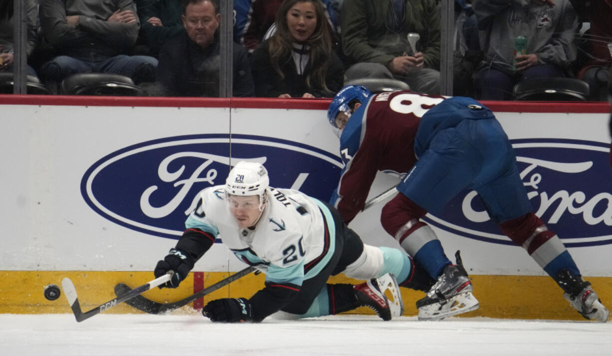 Seattle Kraken right wing Eeli Tolvanen, left, reaches for the puck after being hit by Colorado Avalanche left wing Matt Nieto in the first period of an NHL hockey game Sunday, March 5, 2023, in Denver.