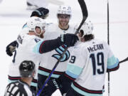 Seattle Kraken defenseman Adam Larsson (6), left wing Jared McCann (19) and center Alex Wennberg (21) celebrate after Larsson scored in overtime of an NHL hockey game against the Dallas Stars, Tuesday, March 21, 2023, in Dallas. The Kraken won 5-4.