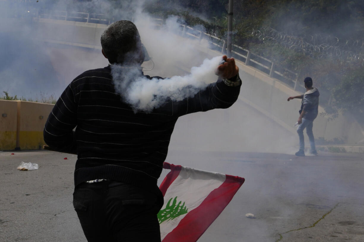 Retired members of the Lebanese security and other protesters return tear gas canisters towards riot police during a protest demanding better pay in Beirut, Lebanon, Wednesday, March 22, 2023. Lebanese security forces fired tear gas to disperse hundreds of protesters who tried to break through the fence leading to the government headquarters in downtown Beirut Wednesday amid widespread anger over the harsh economic conditions in the country.