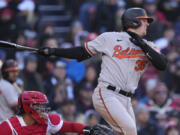 Baltimore Orioles' Adley Rutschman watches the flight of his RBI single in the seventh inning of an opening day baseball game against the Boston Red Sox at Fenway Park, Thursday, March 30, 2023, in Boston.