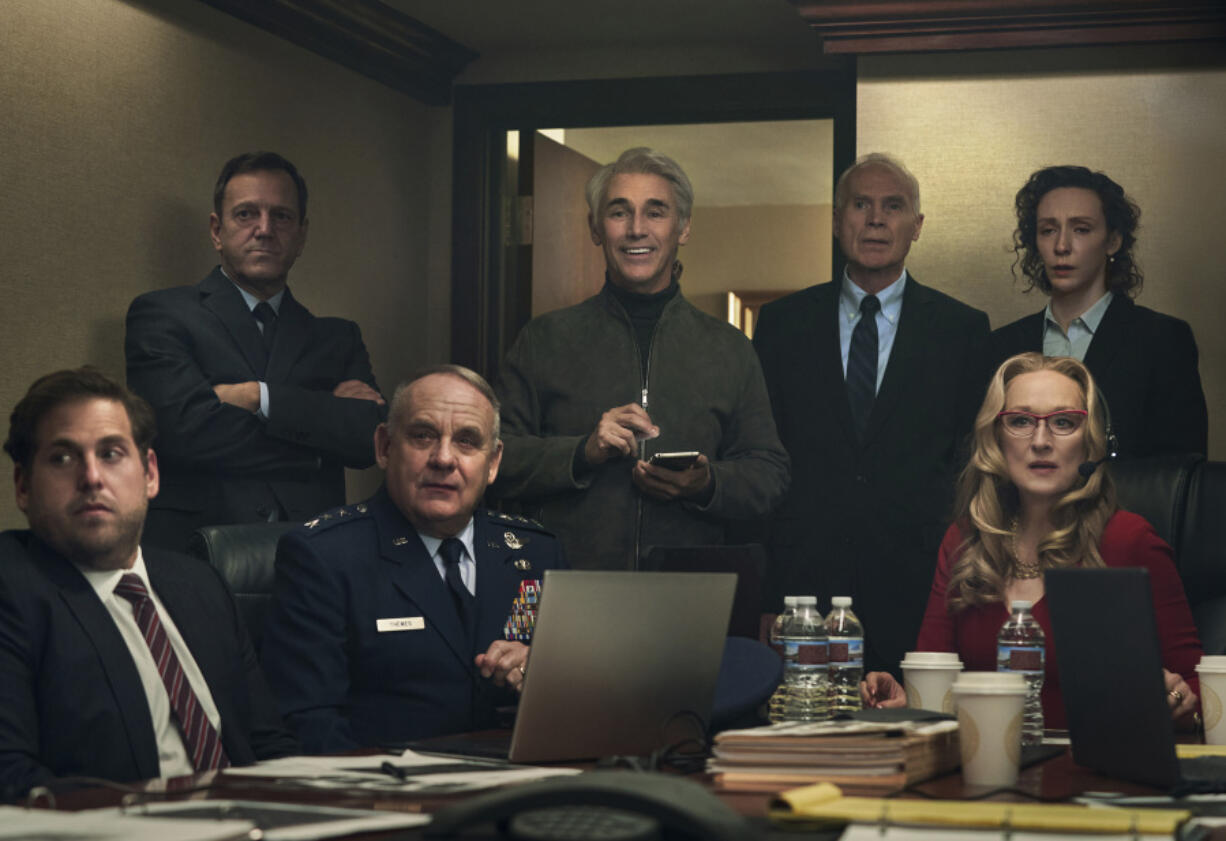 This image released by Netflix shows Mark Rylance as Peter Isherwell, standing center, with main cast members, seated from left, Jonah Hill, Paul Guilfoyle and Meryl Streep in a scene from "Don't Look Up." Rylance portrays tech billionaire Peter Isherwell.