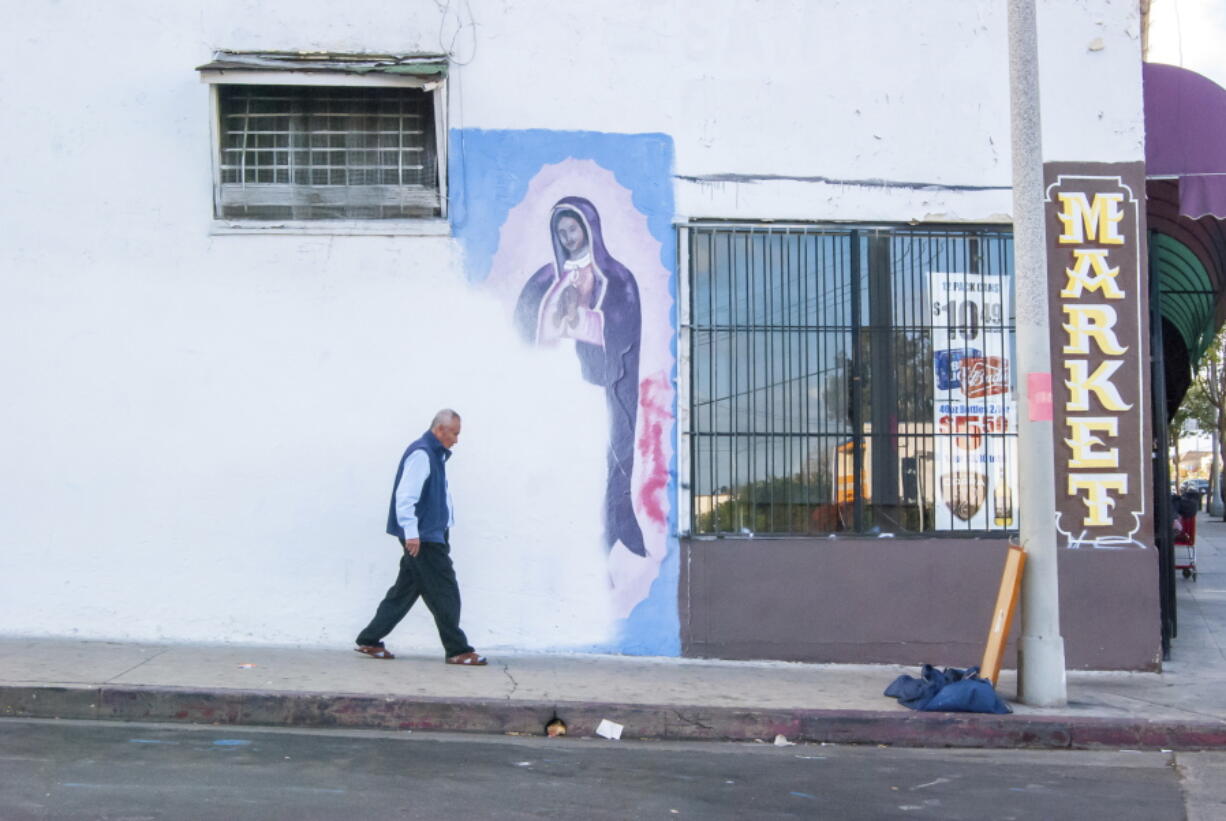 In this photo by Oscar Rodriguez Zapata, a man walks next to a partially-covered Virgin of Guadalupe mural in Los Angeles in 2018. January 2023 marked 10 years since Zapata began documenting images of Guadalupe, at first on his phone for his own pleasure, but eventually taking his hobby more seriously, particularly as he noticed more and more Guadalupe images were vanishing.