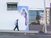 In this photo by Oscar Rodriguez Zapata, a man walks next to a partially-covered Virgin of Guadalupe mural in Los Angeles in 2018. January 2023 marked 10 years since Zapata began documenting images of Guadalupe, at first on his phone for his own pleasure, but eventually taking his hobby more seriously, particularly as he noticed more and more Guadalupe images were vanishing.