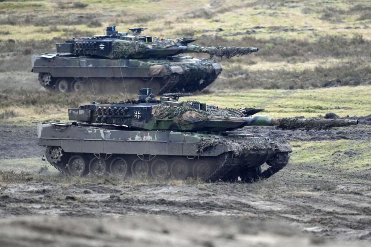 FILE - Two Leopard 2 tanks are seen in action during a visit of German Defense Minister Boris Pistorius at the Field Marshal Rommel Barracks in Augustdorf, Germany, on Feb. 1, 2023. To back future Ukrainian counterattacks, its Western allies have promised new supplies of weapons, including hundreds of tanks and other armored vehicles along with artillery, rockets and other equipment.