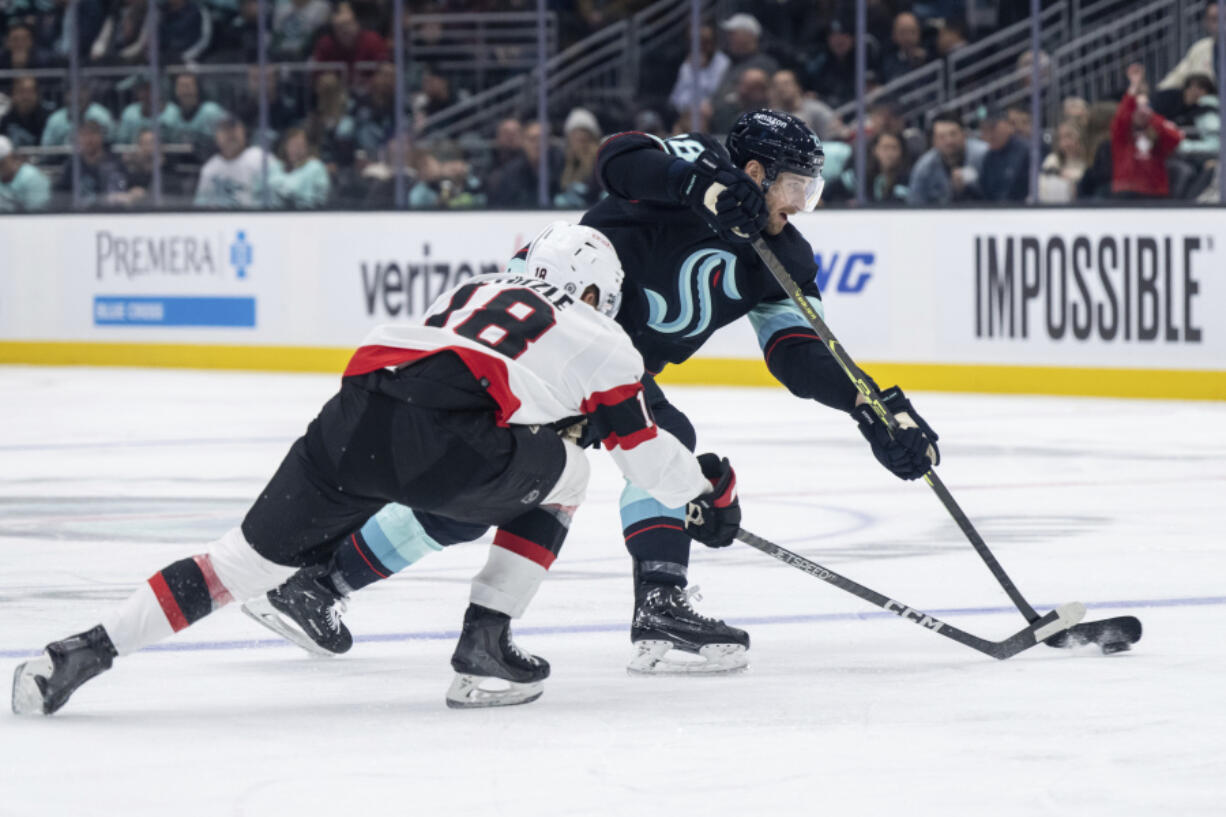 Seattle Kraken defenseman Carson Soucy, right, shoots next to Ottawa Senators forward Tim Stutzle during the second period of an NHL hockey game Thursday, March 9, 2023, in Seattle.