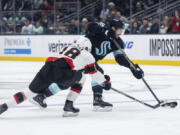 Seattle Kraken defenseman Carson Soucy, right, shoots next to Ottawa Senators forward Tim Stutzle during the second period of an NHL hockey game Thursday, March 9, 2023, in Seattle.