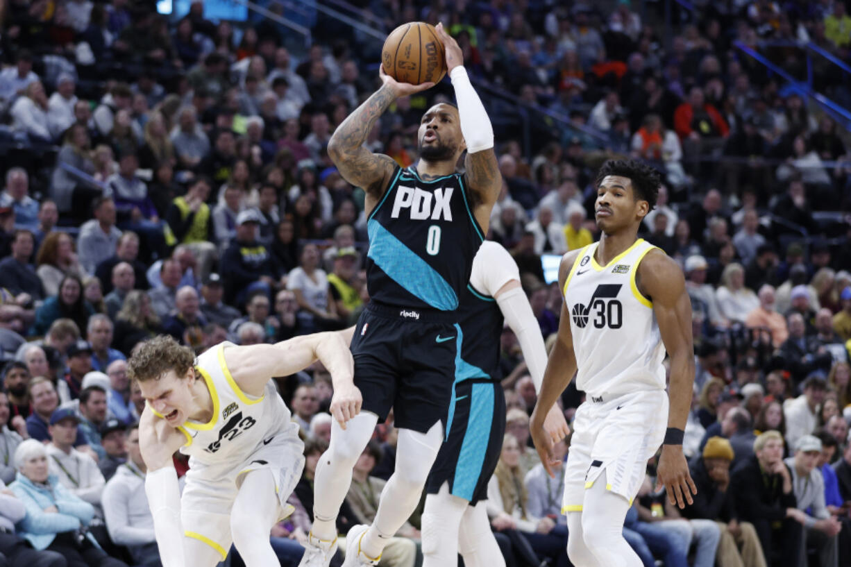 Portland Trail Blazers guard Damian Lillard (0) shoots against the Utah Jazz forward Lauri Markkanen (23), left, and guard Ochai Agbaji (30) in the first half during an NBA basketball game, Wednesday, March 22, 2023, in Salt Lake City.