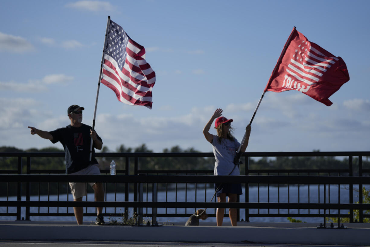 People acknowledge supportive honks from passing cars as they show support for former President Donald Trump a day after he was indicted by a Manhattan grand jury, Thursday, March 30, 2023, near Trump's Mar-a-Lago estate in Palm Beach, Fla.