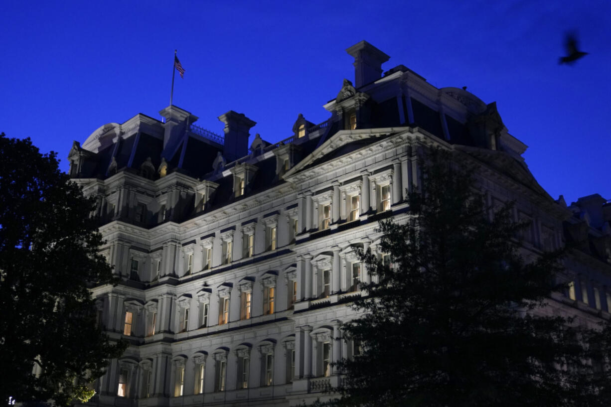 FILE - A bird flies over the Eisenhower Executive Office Building on the White House complex at dusk, June 1, 2021, in Washington. There's been a fire at the Eisenhower Executive Office Building next to the White House, leading to the evacuation of workers as firefighters responded to the call. D.C. Fire and Emergency Medical Services tweeted that a defective cooling motor in the basement caused the fire Friday morning. No injuries were reported.