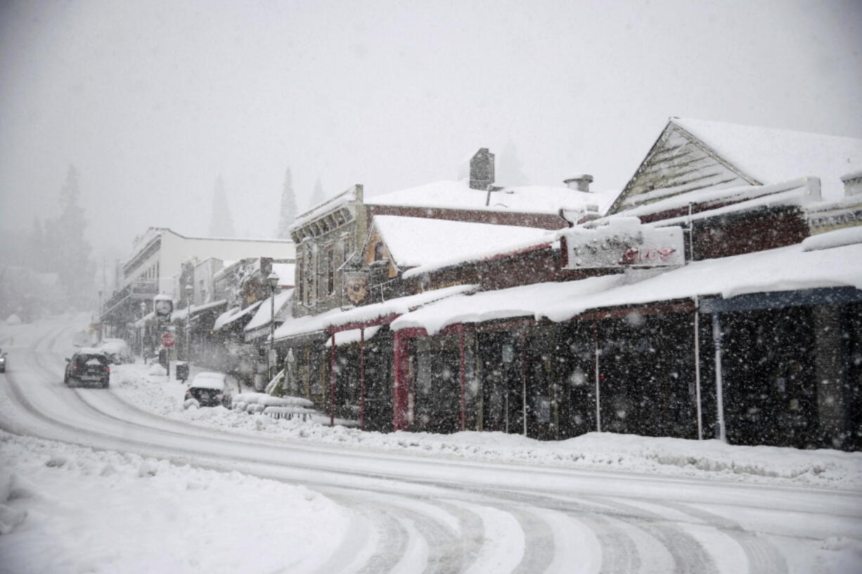 Vehicles make their way along Main Street through heavy snowfall in Grass Valley, Calif., Tuesday, Feb. 28, 2023.