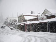 Vehicles make their way along Main Street through heavy snowfall in Grass Valley, Calif., Tuesday, Feb. 28, 2023.