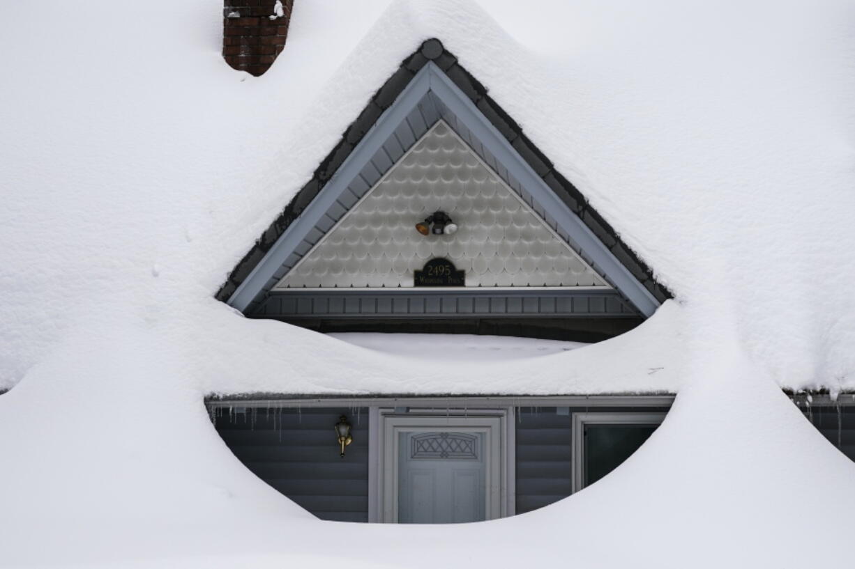 Snow is piled up on a home in Running Springs, Calif., Tuesday, Feb. 28, 2023. Beleaguered Californians got hit again Tuesday as a new winter storm moved into the already drenched and snow-plastered state, with blizzard warnings blanketing the Sierra Nevada and forecasters warning residents that any travel was dangerous. (AP Photo/Jae C.