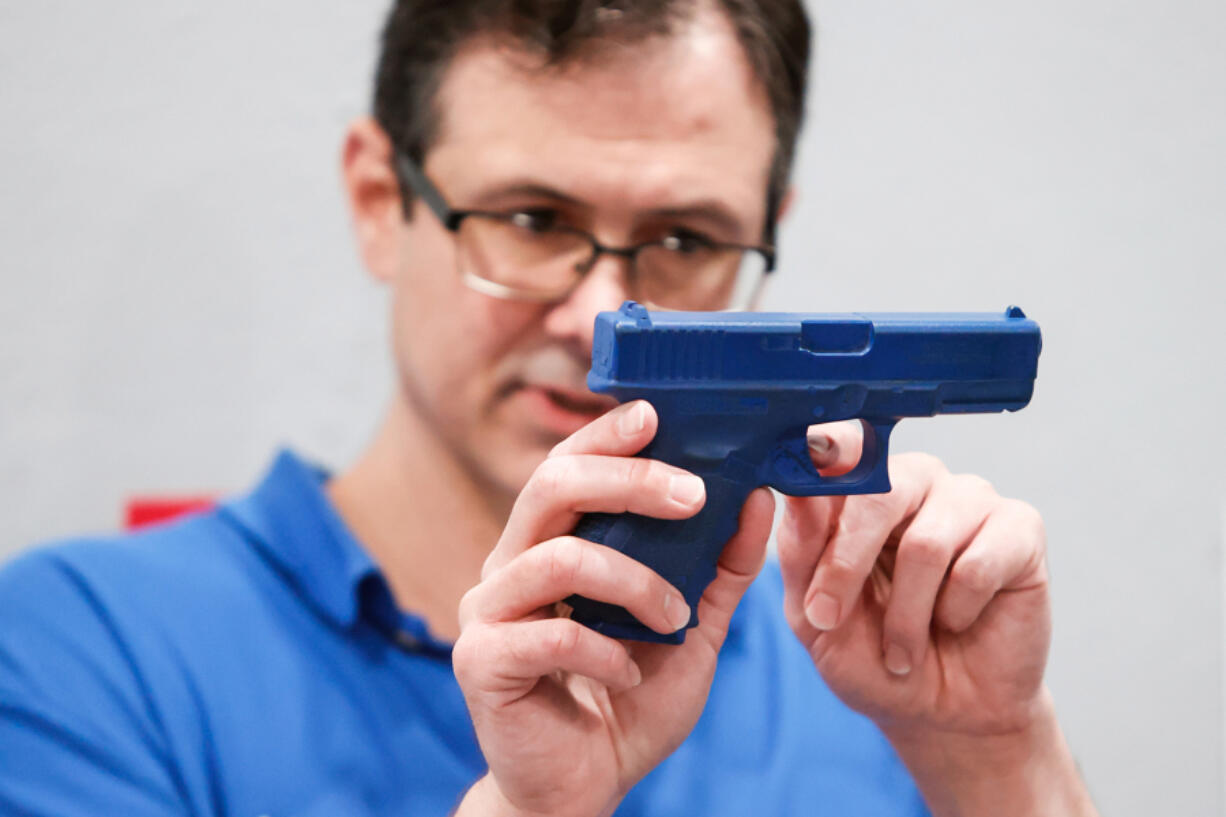 Brent Adair holds a "blue gun" while teaching a concealed weapons permit class at Brandon Gun School. Adair does not support Florida's new law allowing permitless concealed carry without mandatory gun safety training.